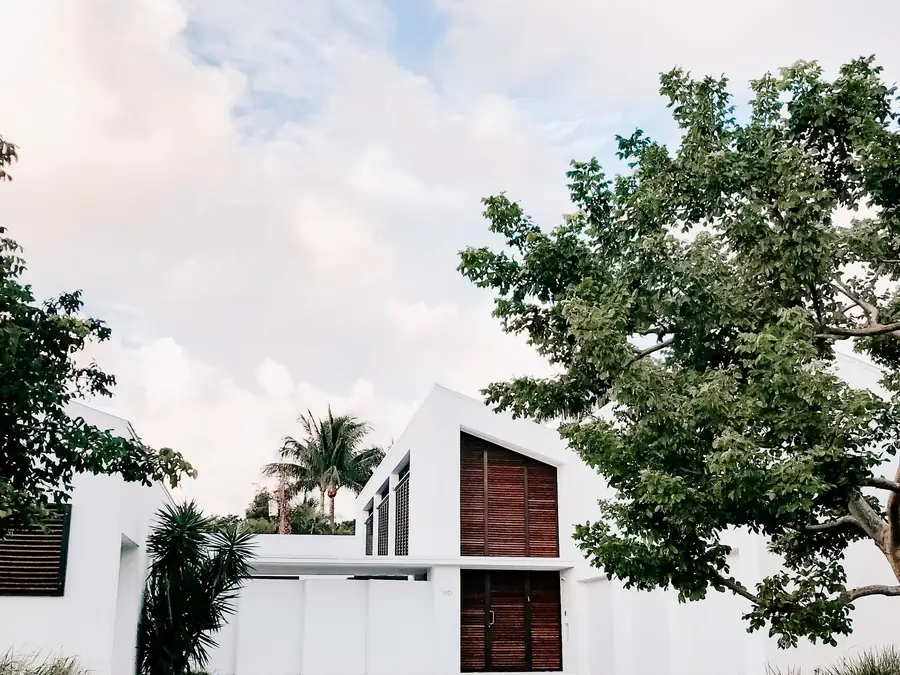 Fachada de residência unifamiliar com volumes brancos e jardim