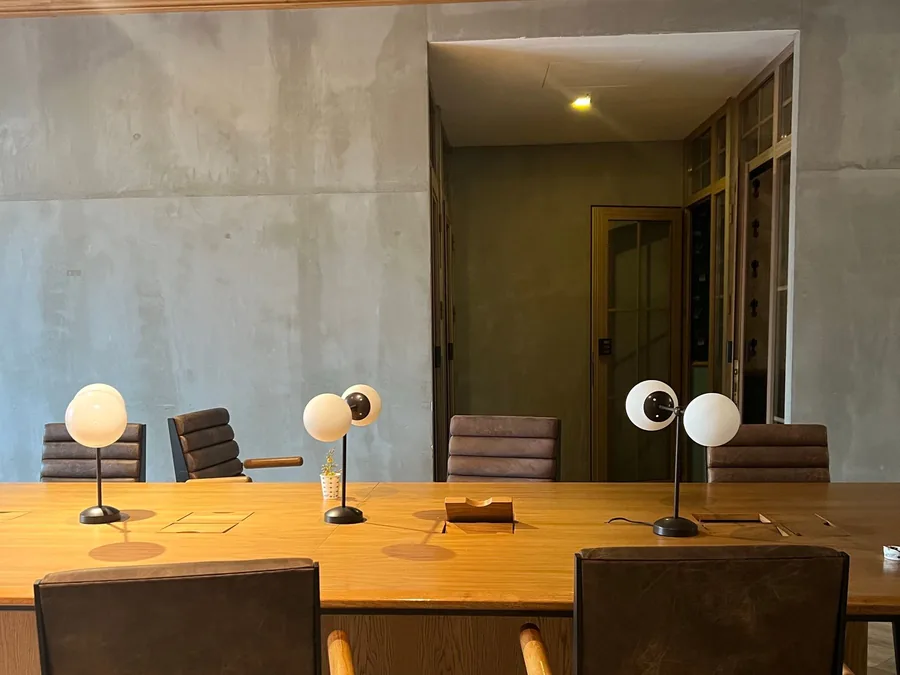 Sala de reunião com paredes de concreto aparente e mesa de madeira maciça